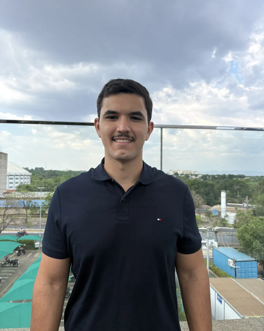 Théo Trindade Bernini, fundador da Bernini IA, sorrindo em um terraço com Cuiabá ao fundo